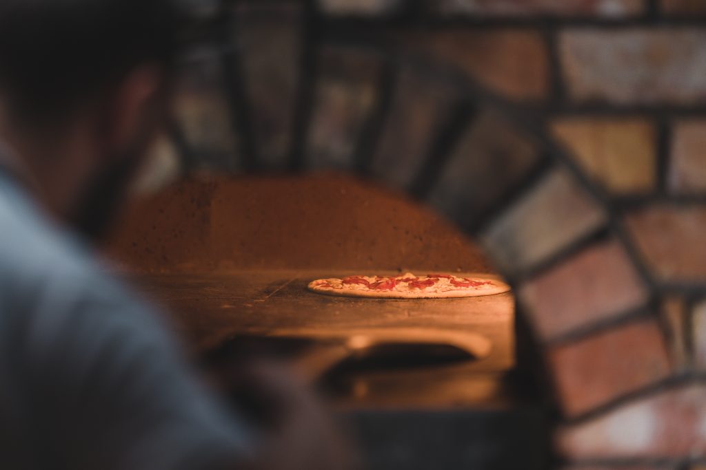 pizza placed into stone oven to bake.