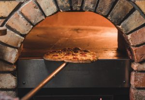 stone baked pizza being taken out of oven. firehouse pizza enniskillen - pizza in enniskillen