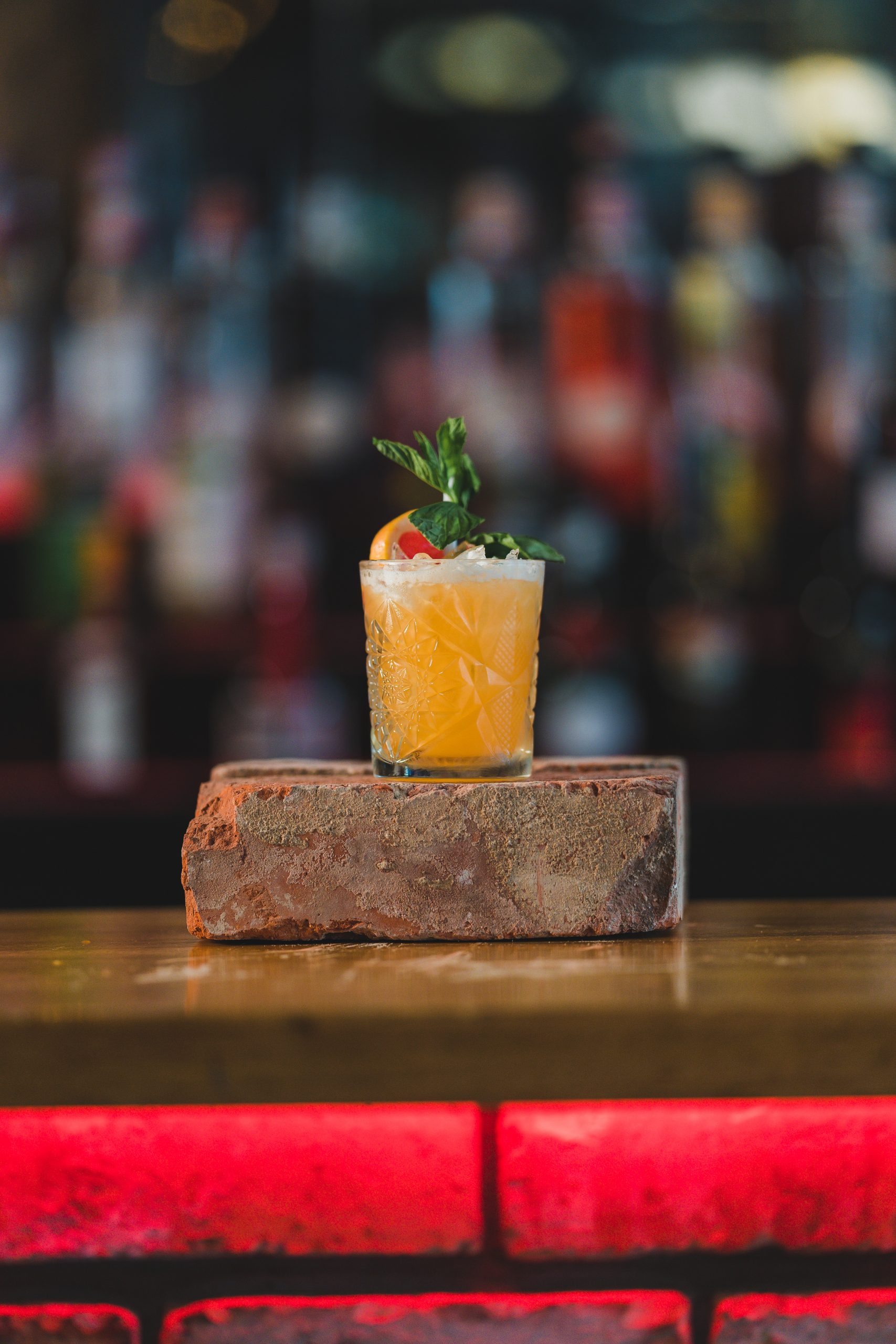 small cocktail glass sitting on top of brick on a bar.