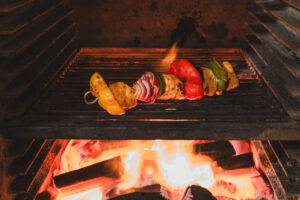 A chicken and vegetable skewer being grilled with wood burning flames beneath. best place to eat in enniskillen